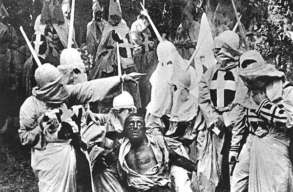Actors costumed in the full regalia of the Ku Klux Klan chase down a white actor in blackface in a still from 'The Birth of a Nation,' the first feature-length film, directed by D. W. Griffith, California, 1914.